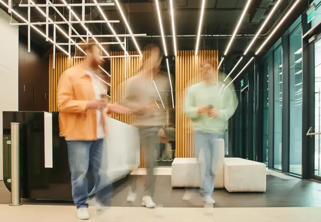 Blurred motion of professionals walking and conversing in a modern office lobby.