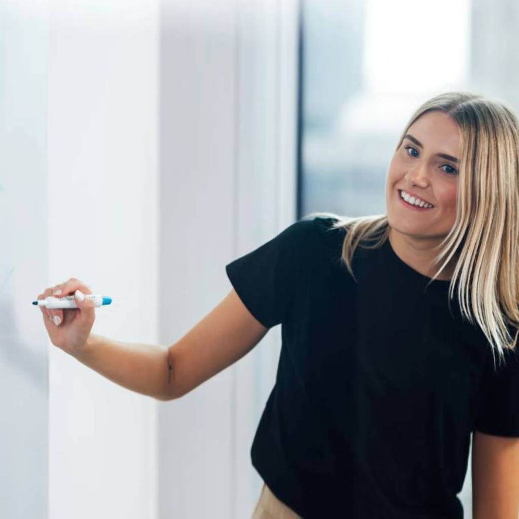 Professional presenting ideas on a whiteboard in a modern office setting.