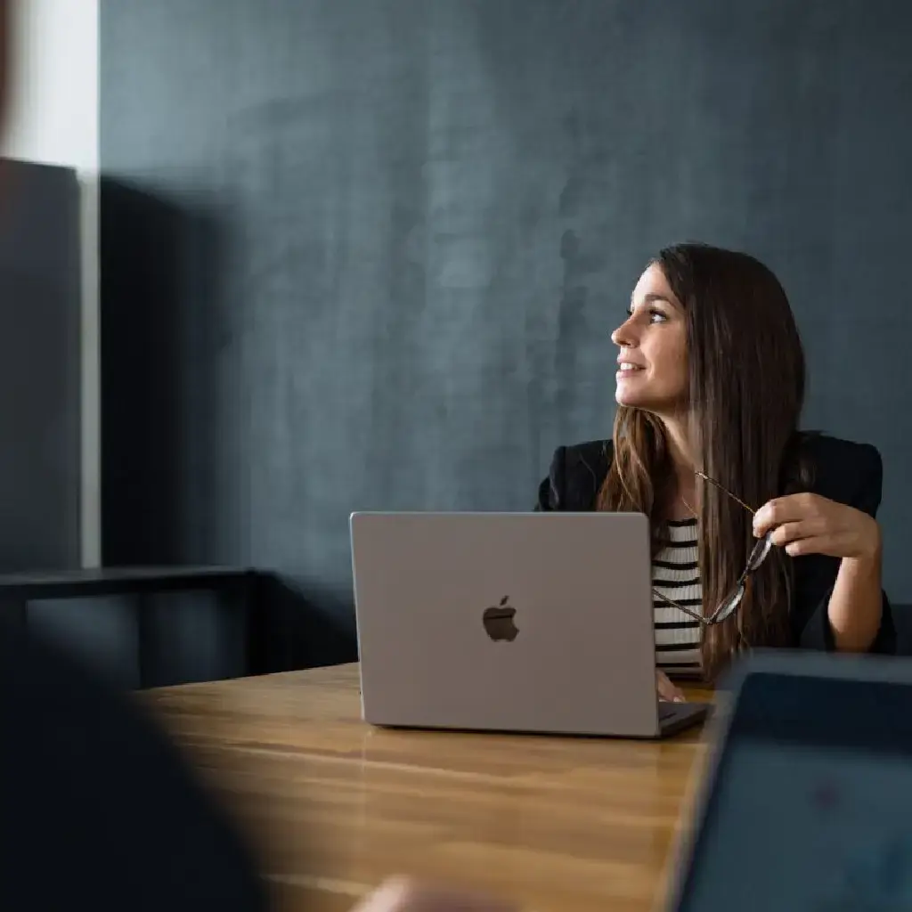 Business professional engaged in a discussion while working on a laptop