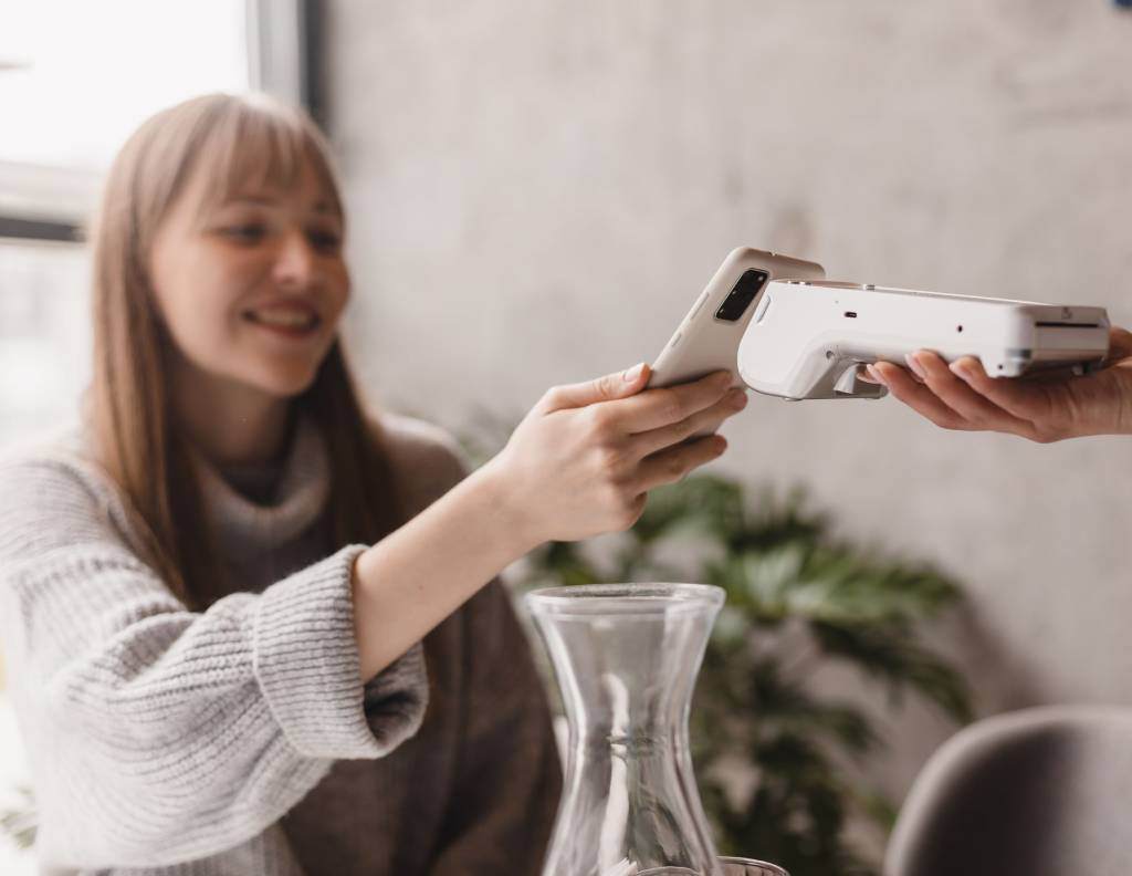 Customer making a contactless payment with a smartphone at a café