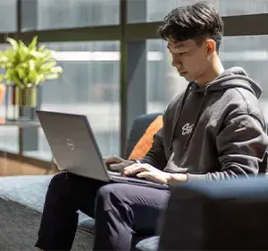 endava employee sitting on office couch while working on laptop 