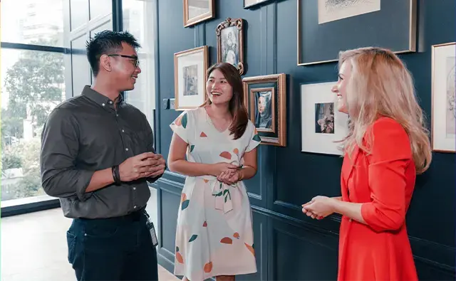 Colleagues engaged in conversation near a gallery-style wall in a stylish office setting