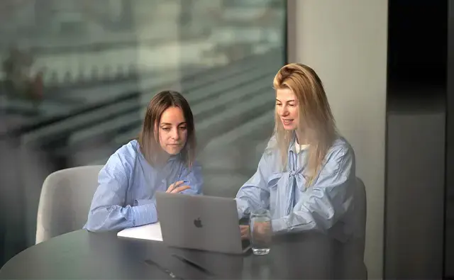 Two woman seated in front of notebook