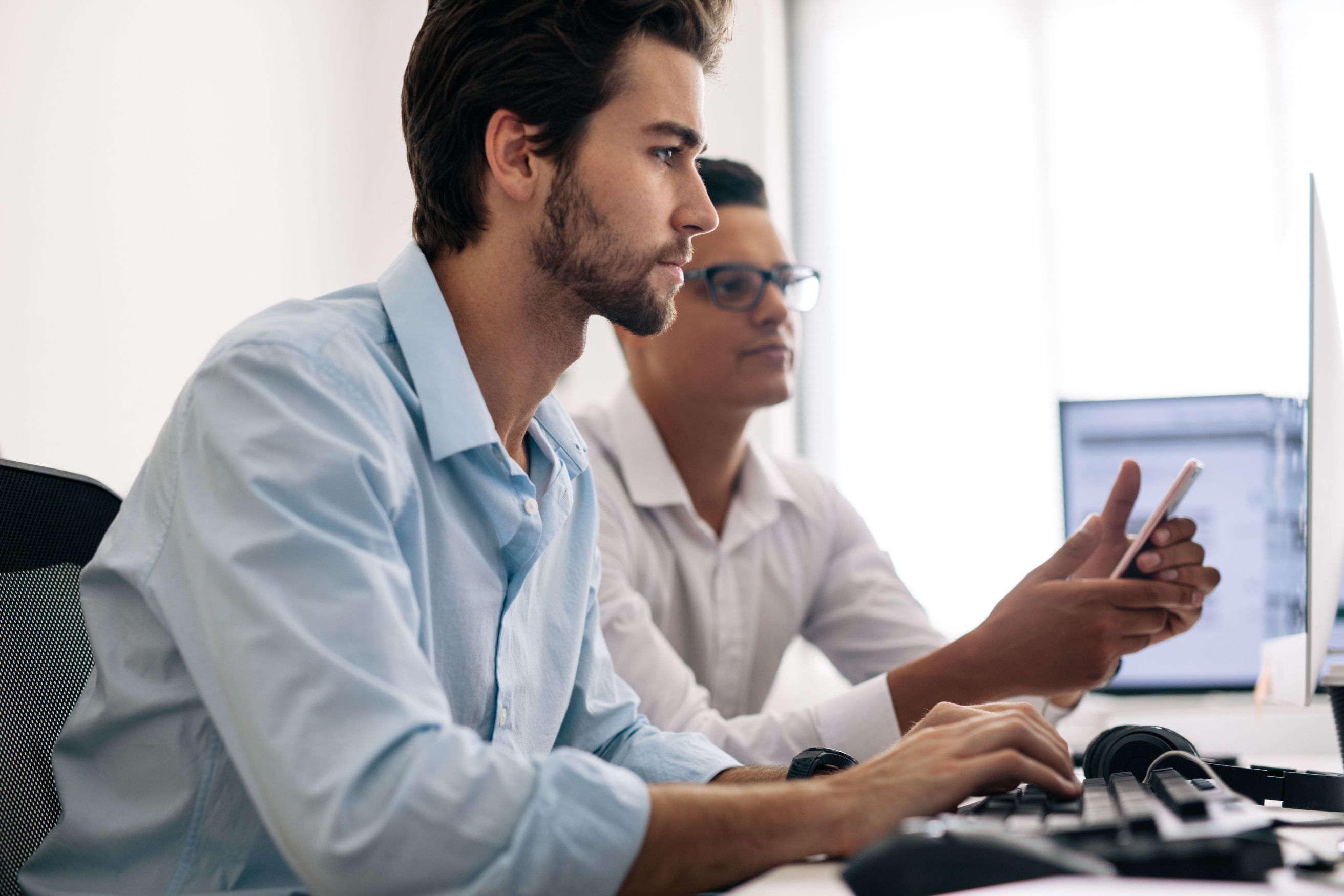 Two men working on computers in an office, focusing on Payments Strategy to modernize National Insurer.