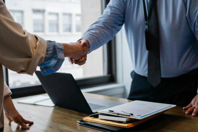 Two people handshake hands in an office