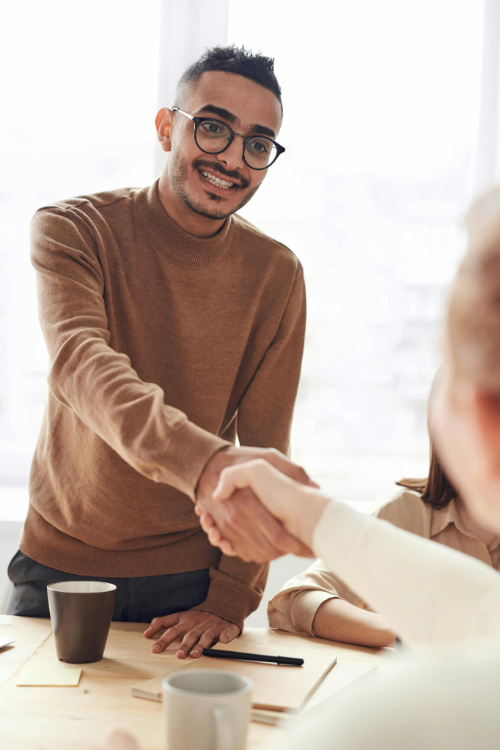 A man handshaking another colleague at work