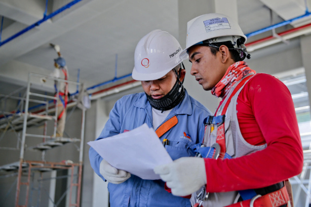 Two construction workers reviewing a paper