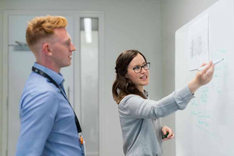 A man and a woman writing on a whiteboard  