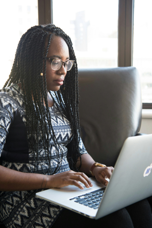 A woman sitting down and writing on a laptop