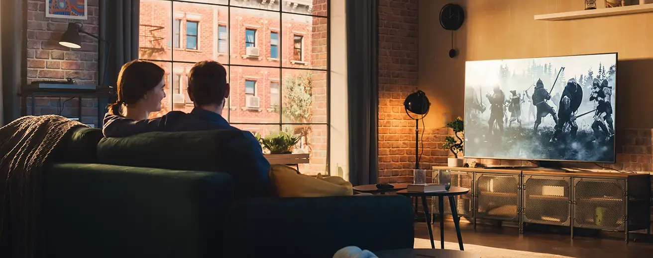 couple sitting on the couch and watching a movie on their television at home