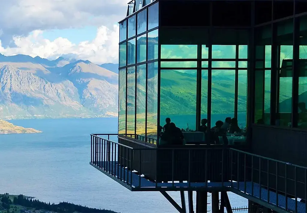 glass building on high platform with mountain and lake view