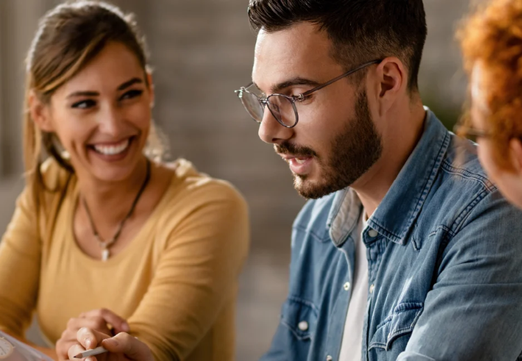 Man with glasses pointing to data while talking with female coworkers