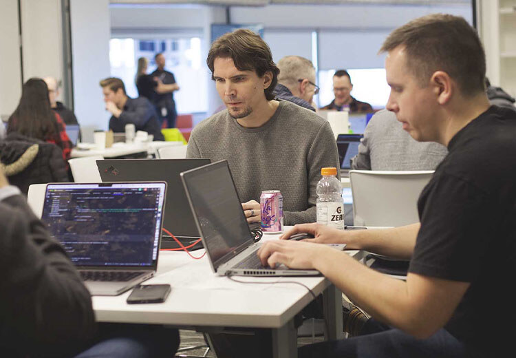 two tech engineers working on their laptops during the Endava Microsoft Hackathon