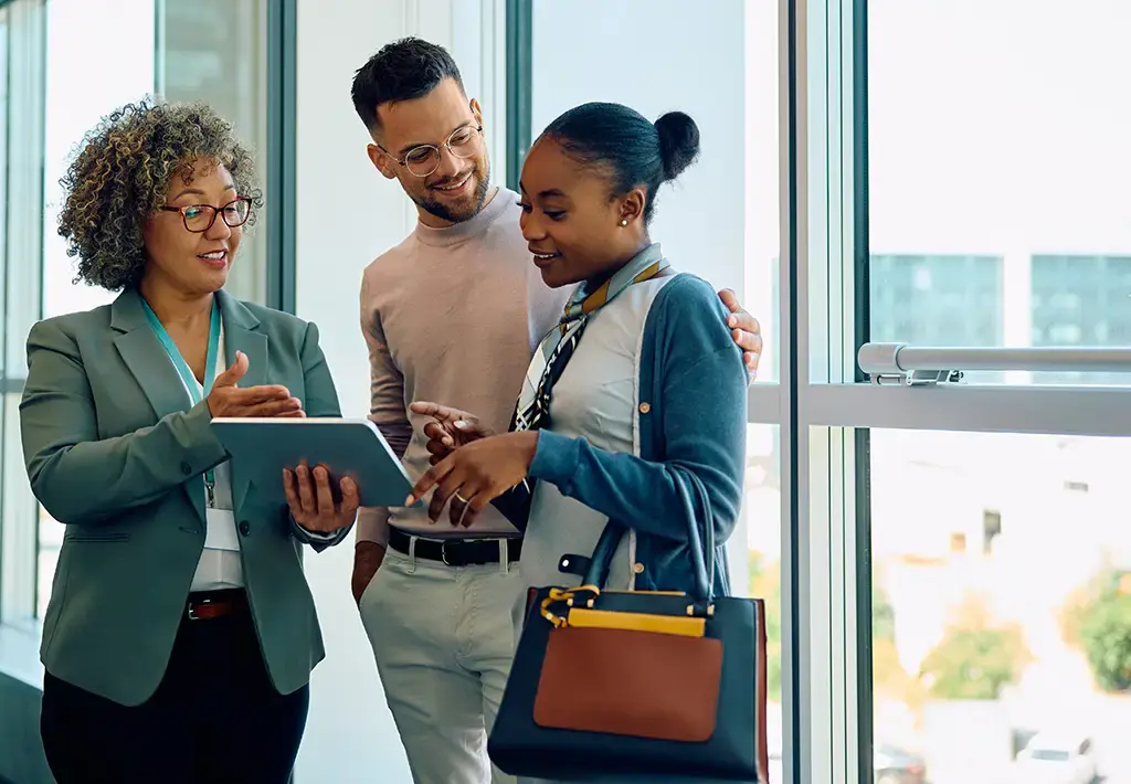 Salesperson showing details on a tablet to a couple in a modern office setting