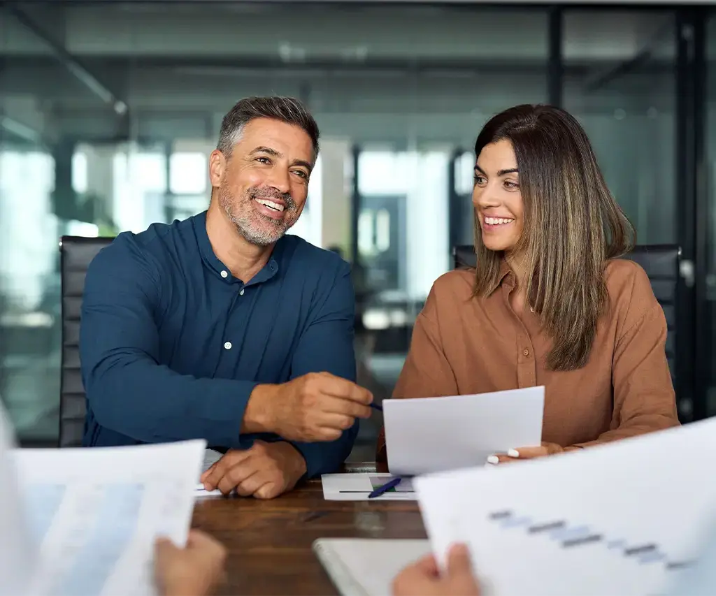 man and woman reviewing spreadsheets in office conference room