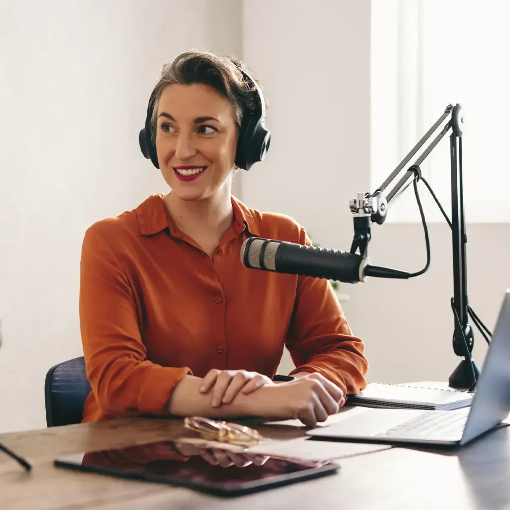 two women recording interview using microphones and headsets and laptops