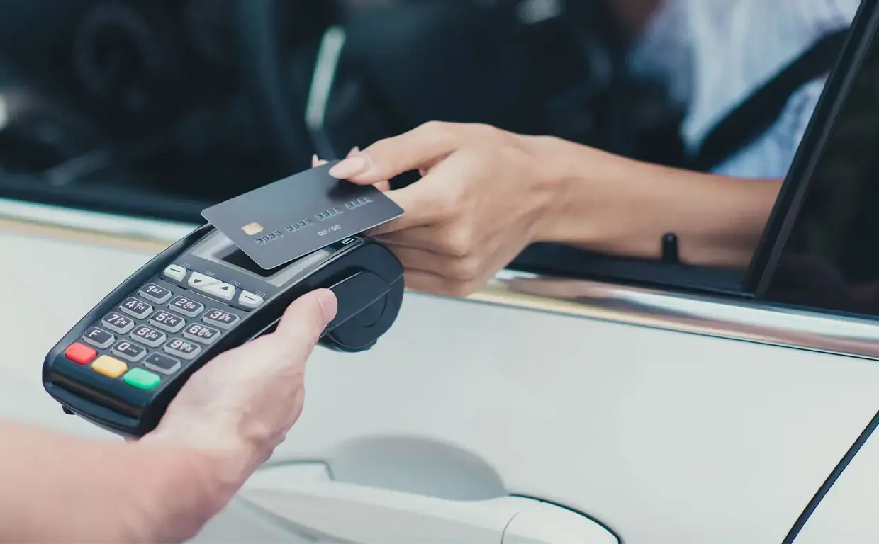 woman paying by credit card from within her automobile