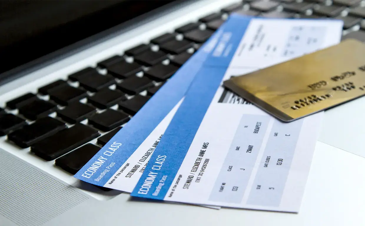 credit card laying on top of airline tickets on top of laptop keyboard