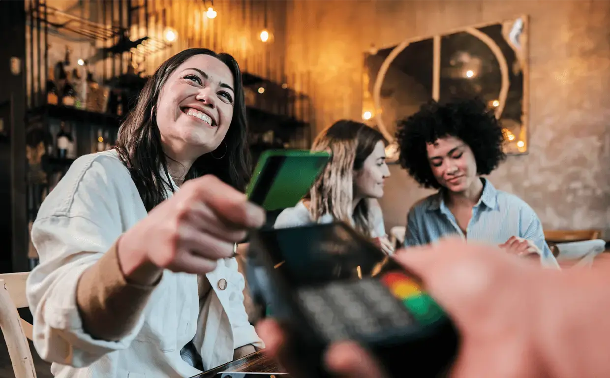 happy young woman paying with her credit card at a restaurant