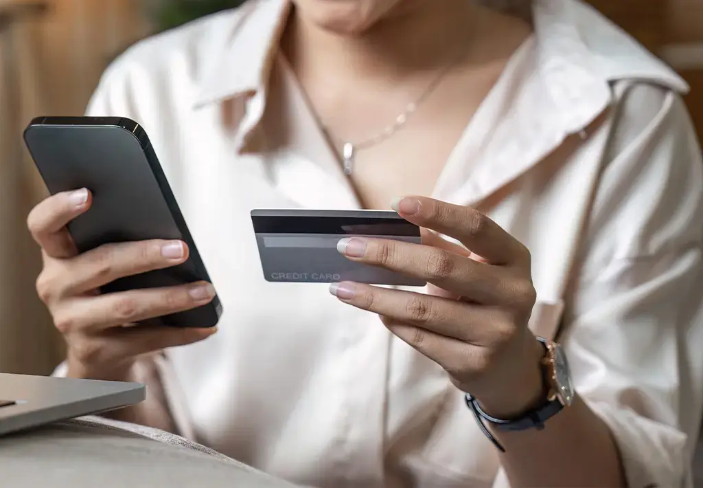 person holding card and phone for retail payment