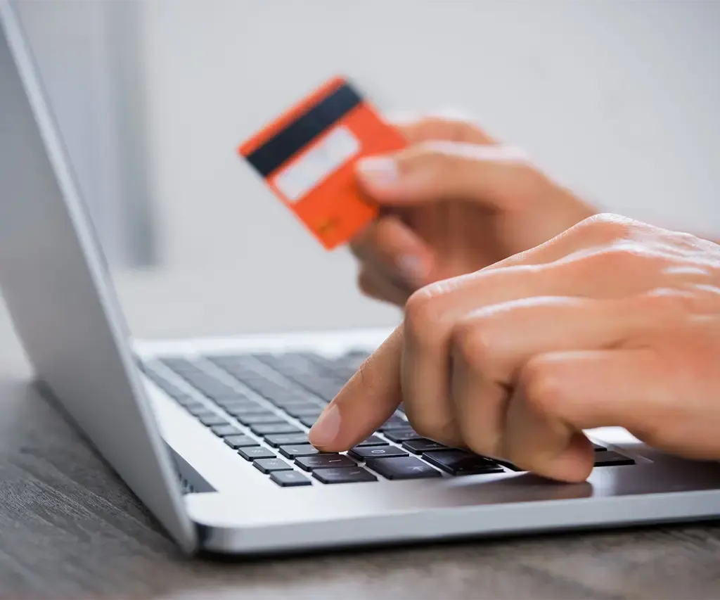 closeup of mans hand typing credit card information into laptop