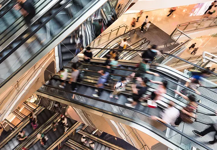 Retail customers riding the escalors in shopping mall