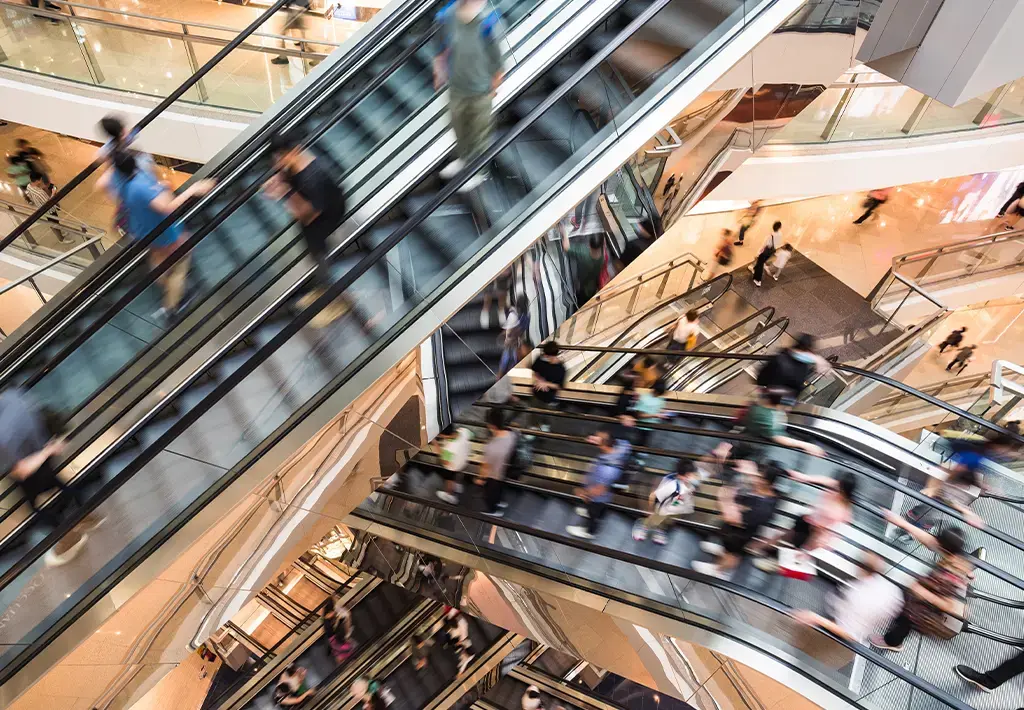 retail customers riding the shopping mall escalors