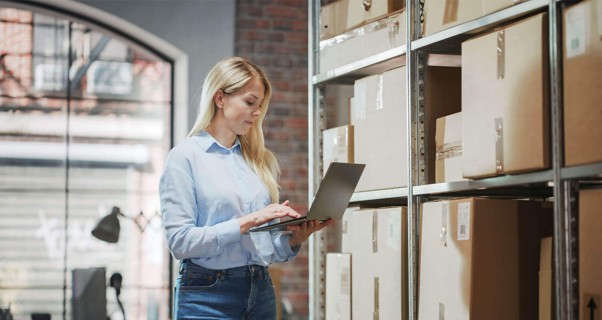 supply chain expert working on her laptop in front of shipping boxes