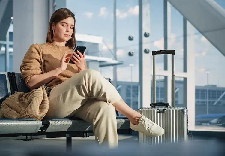 woman sitting at airport checking flight mobile phone