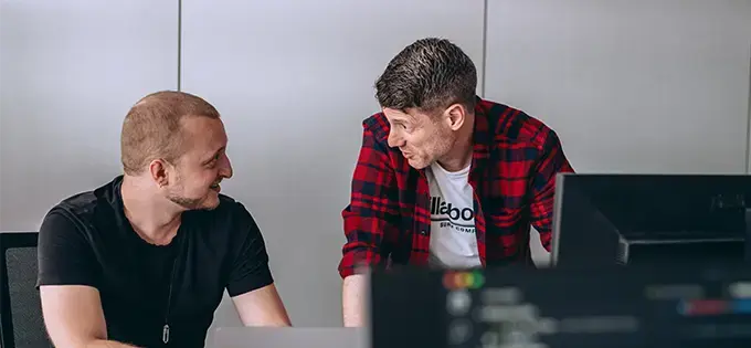 two male Endava employees discussing work at a desk