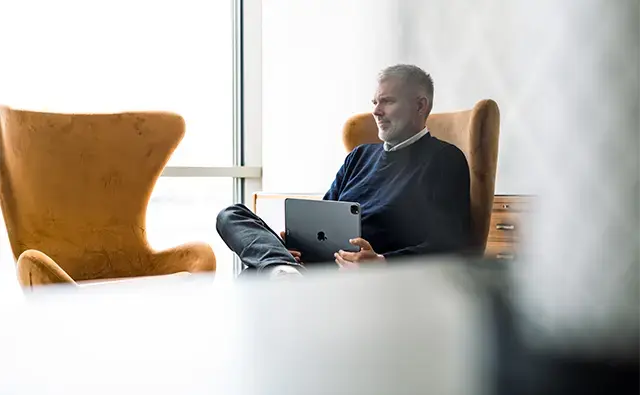 man sitting in fancy orange office chair holding a laptop