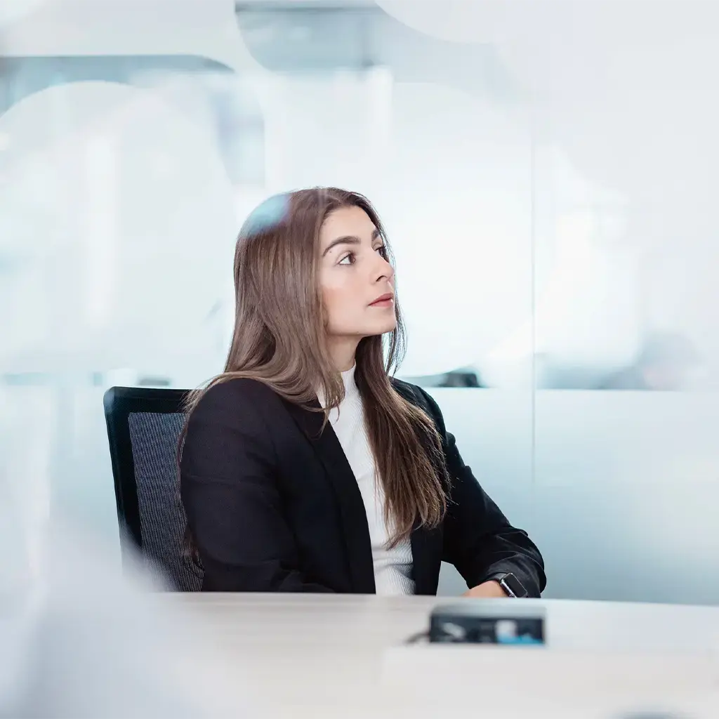 business woman looks focused in dark suit sitting in white office 