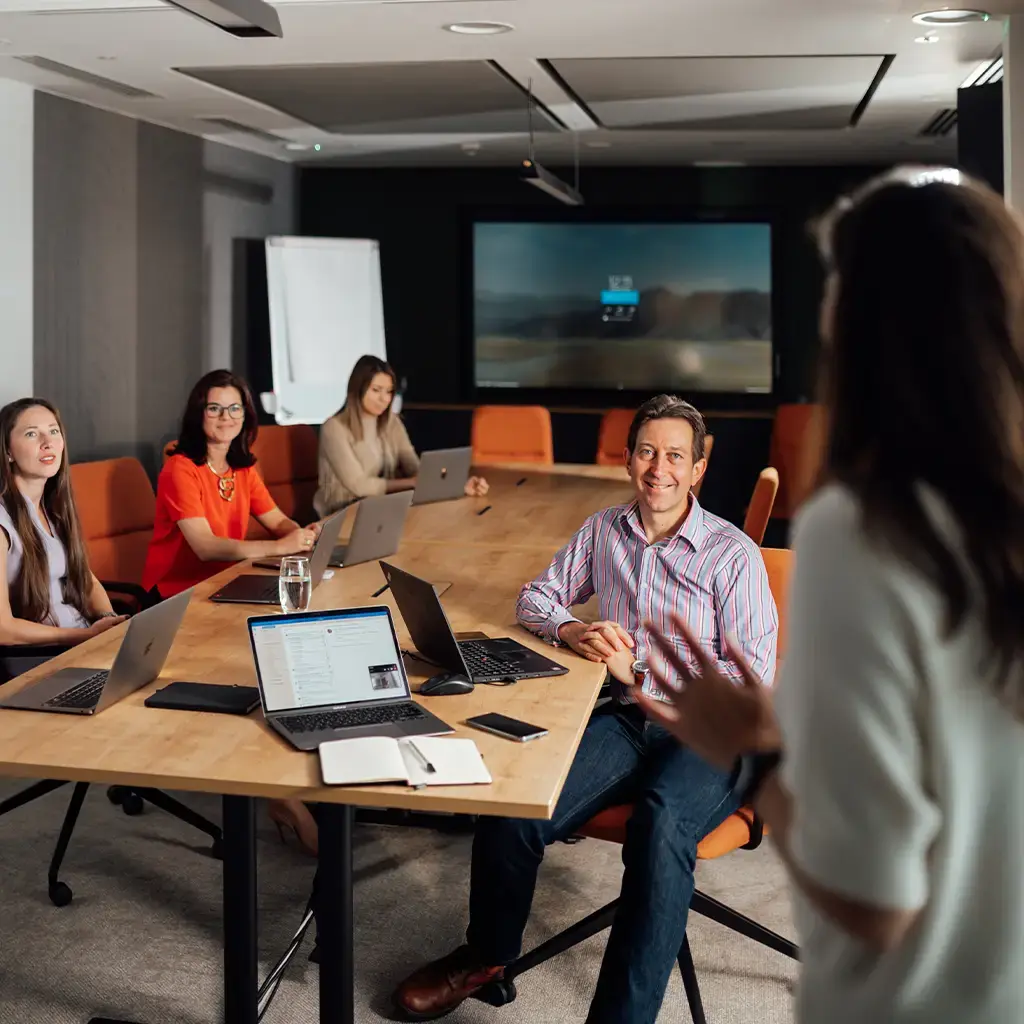 Team collaborating in a modern conference room with laptops and a presentation screen.