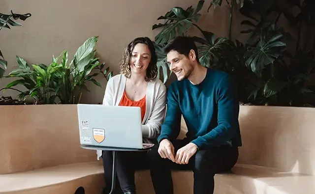 A woman and a man working together on a laptop.