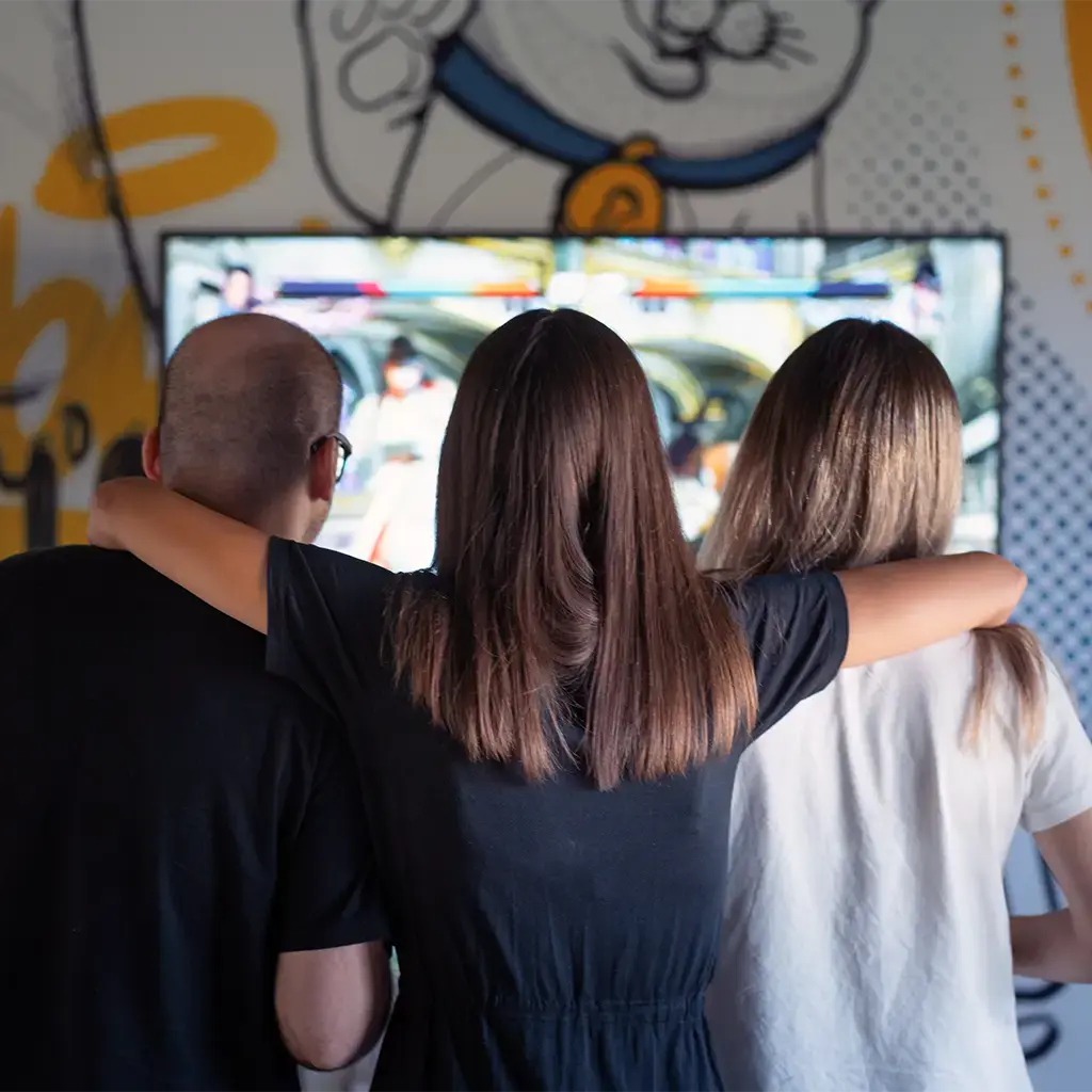 Alt-text: Three colleagues enjoying a video game together in a casual, creative office space with colorful wall art