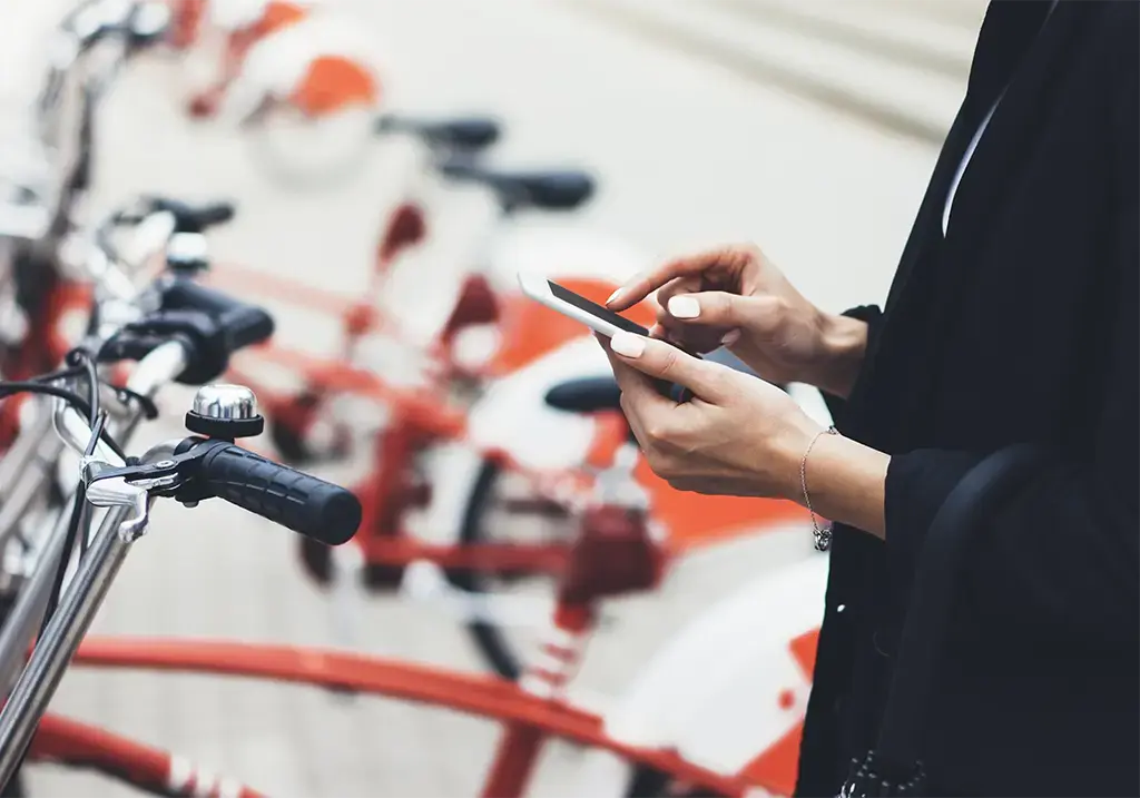 A woman using her phone near line of bicycles