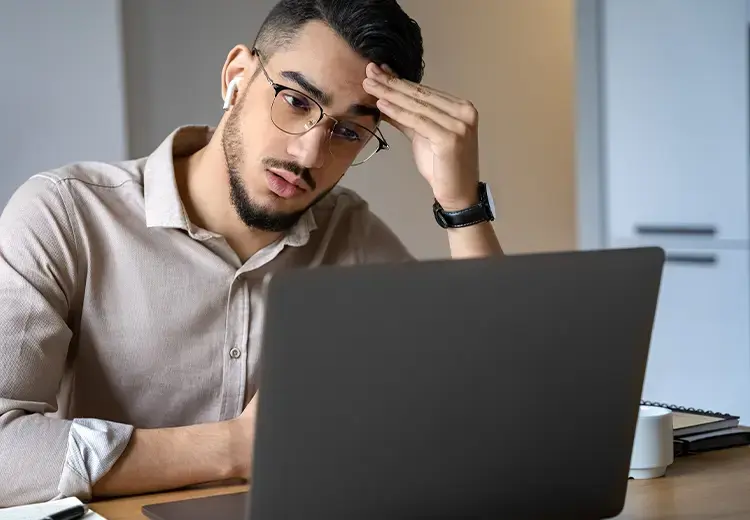 man in glasses focusing on laptop screen