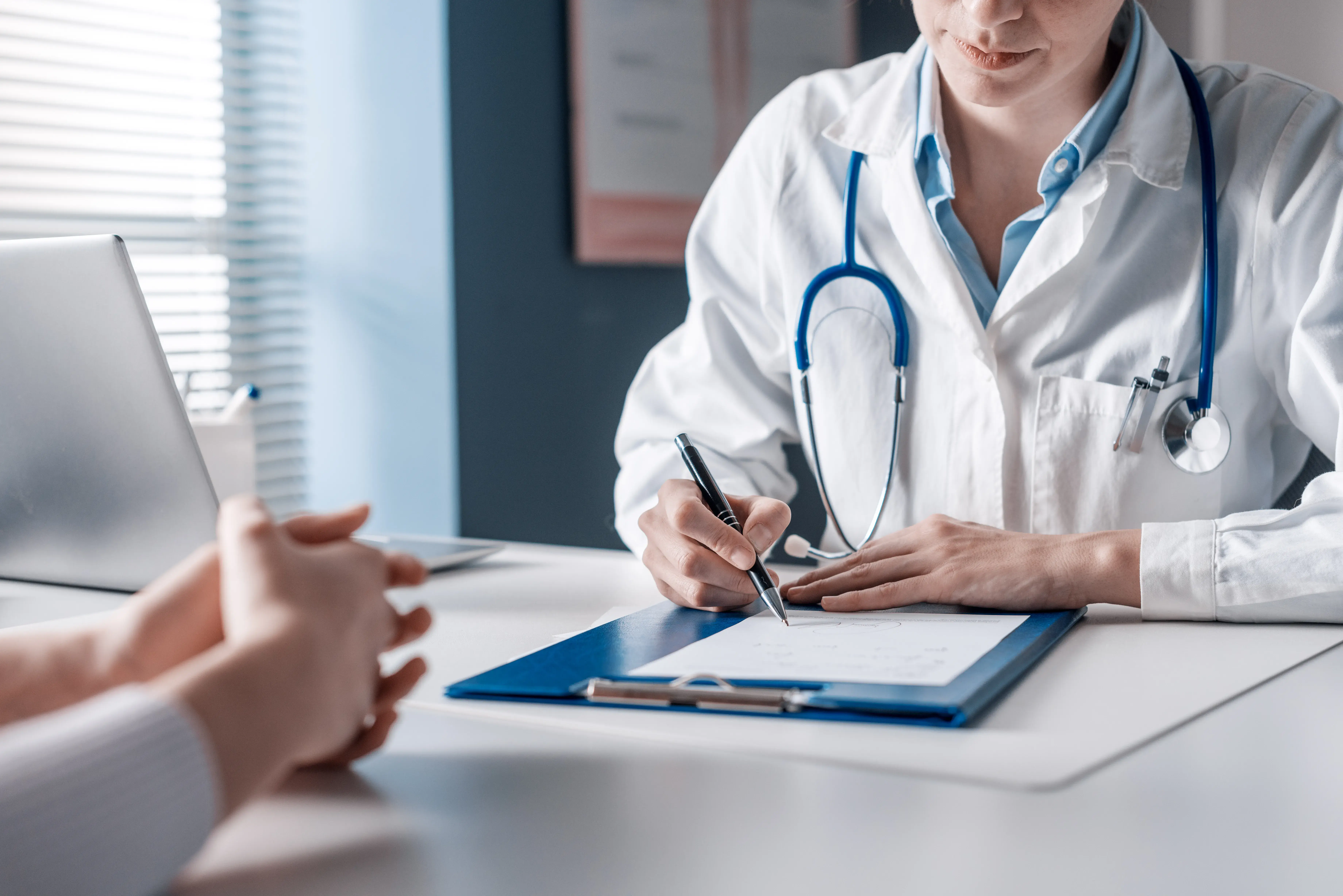 A doctor writing on a clipboard, ensuring compliance and delivering healthcare solutions on time and with expertise.