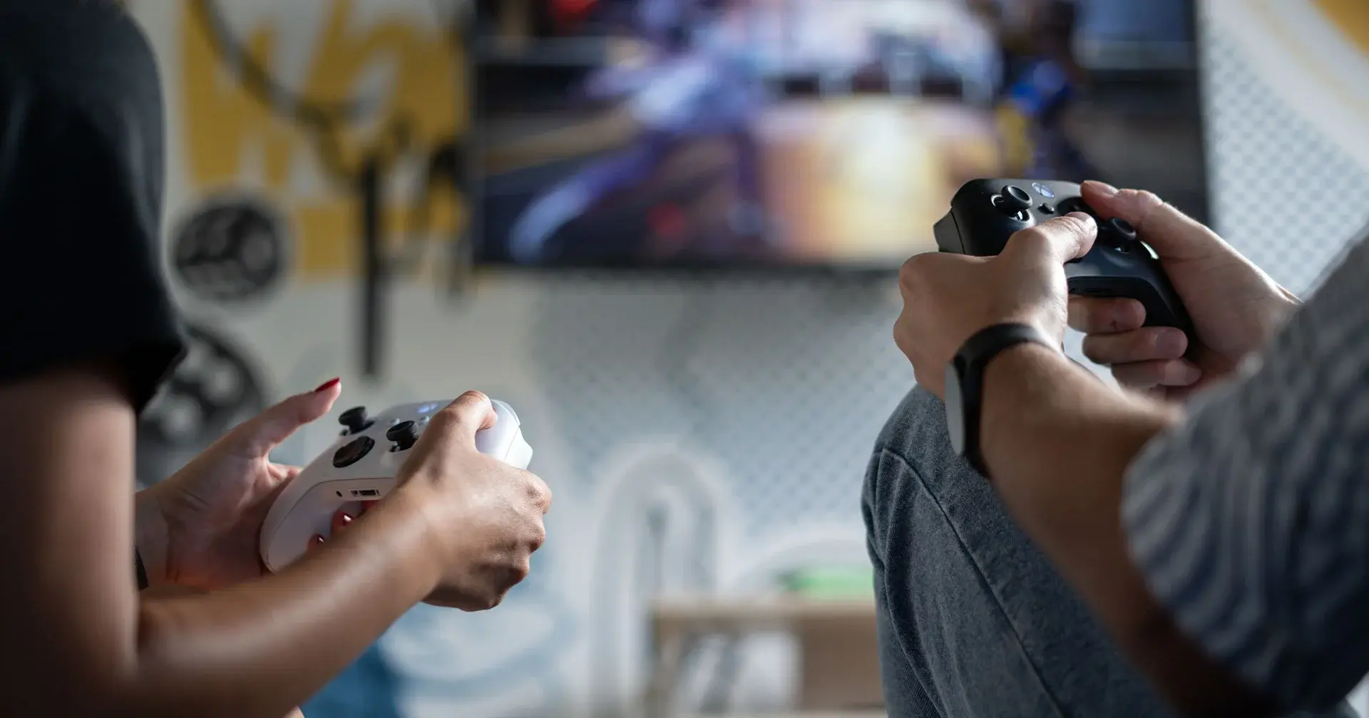 a man and women holding Xbox video game controllers and playing a video game together