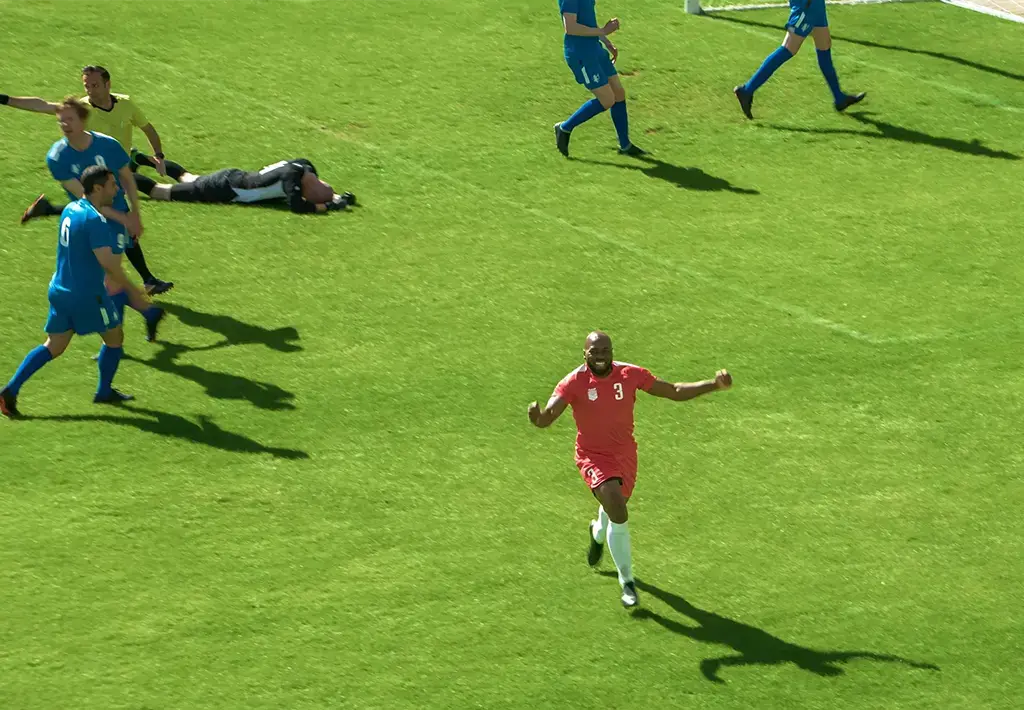 soccer player in red shirt on green field of blue shirted players