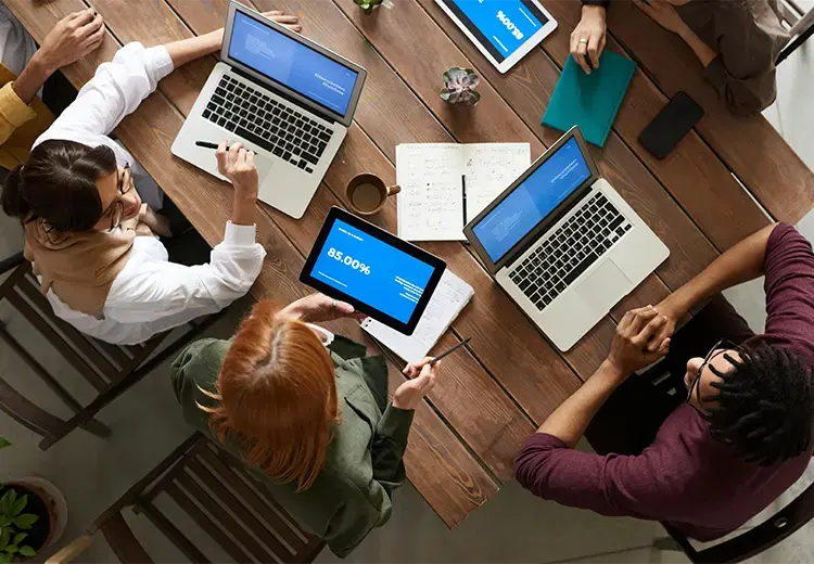 A group of people sitting at the table working on laptops