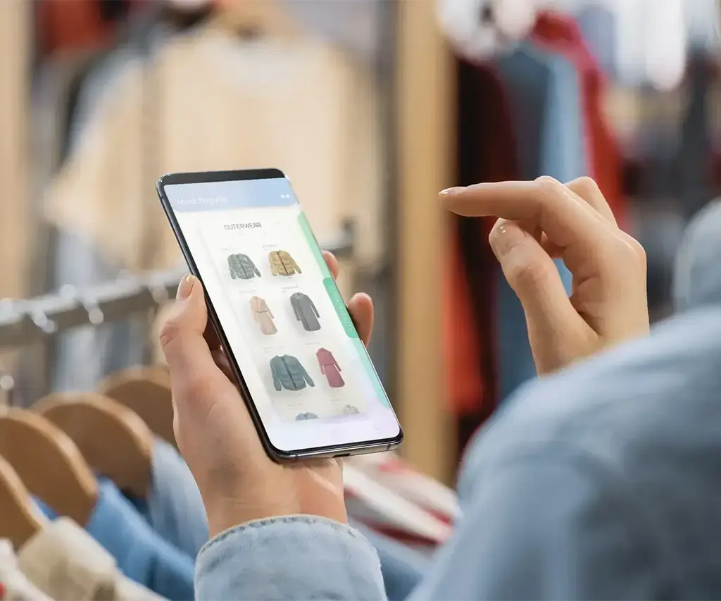 person viewing clothing items on mobile app in retail store