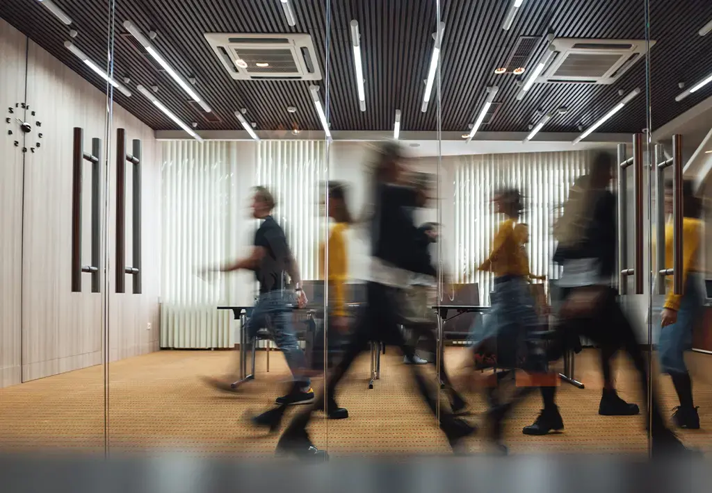 motion blurred workers walking down hallways toward wall with clock