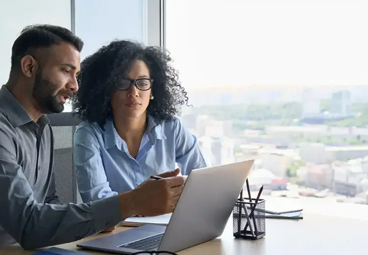 two coworkers looking at laptop