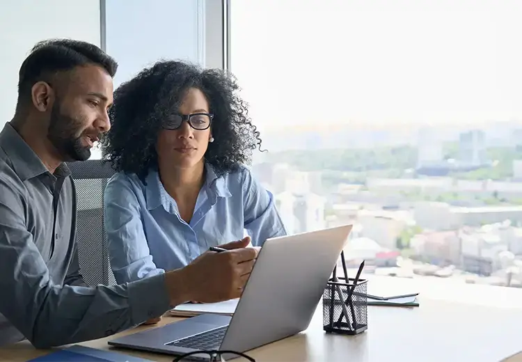 two coworkers looking at laptop