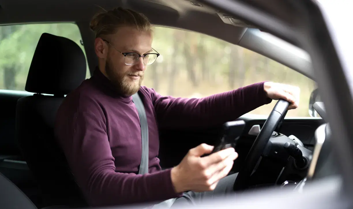 A man sitting in the car using in-vehicle payment cell phone.