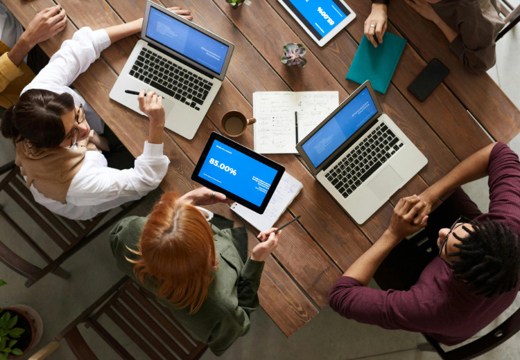 A group of people sitting at the table working on laptops