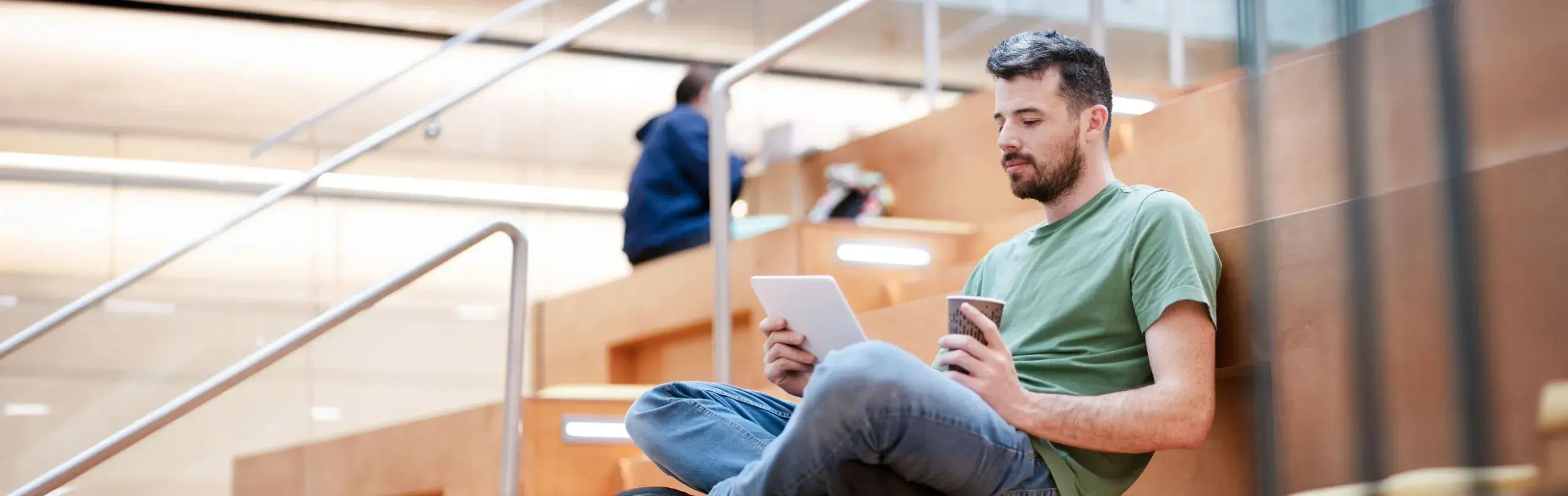 Man sitted at stair with tablet and a coffee