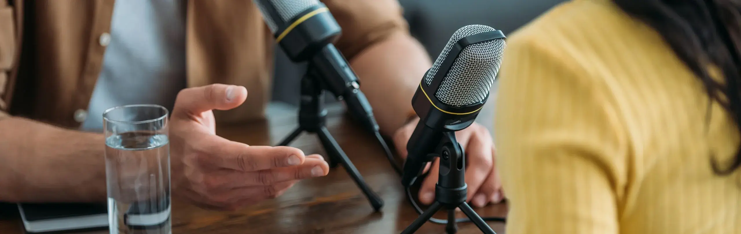 close up on microphone and two people on podcast