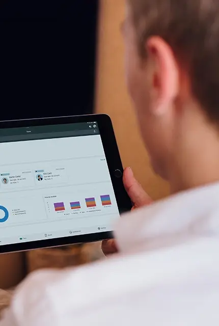 A man sitting on a couch, holding a tablet computer.